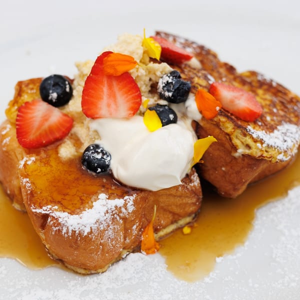 Avalon By Day French toast with strawberries, blueberries, whipped cream, syrup, and powdered sugar.